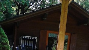 Un área de hidromasaje al aire libre con cubierta de madera, sillas de descanso y una mesa.