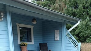 A blue house with a wooden deck, a chair, and two spherical objects on the deck. - Dachsbau by Interhome (Winsen / Aller)