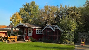 Een rode woning met een witte veranda en een garage.
