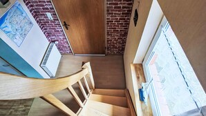 A staircase with wooden steps and a handrail, a wooden door, a brick wall, and a window with a view. - Apartment Marion by Interhome (Greetsiel)