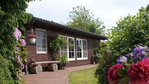 Ein Holzhaus mit einem Ziegelweg, der zu einer Bank führt.