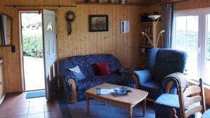 Ein gemütliches Zimmer mit Holzwänden, einer Couch, einem Sessel und einem kleinen Tisch.