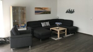 A modern living room with a sectional sofa, a small side table, and a glass cabinet. - in Sehestedt mit Garten by Interhome (Jade)