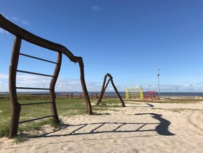 Uma praia arenosa com estruturas de madeira e um poste amarelo.