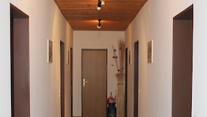 Ein Korridor mit Holzboden, braunem Teppich und einer Tür am Ende.