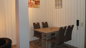 Ein kleiner Besprechungsraum mit einem Holztisch und vier Stühlen, weißen Wandverkleidungen und einer gerahmten Karte an der Wand.