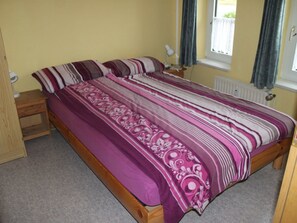 Una camera da letto con un letto, comodini in legno, una lampada e una finestra con tende.