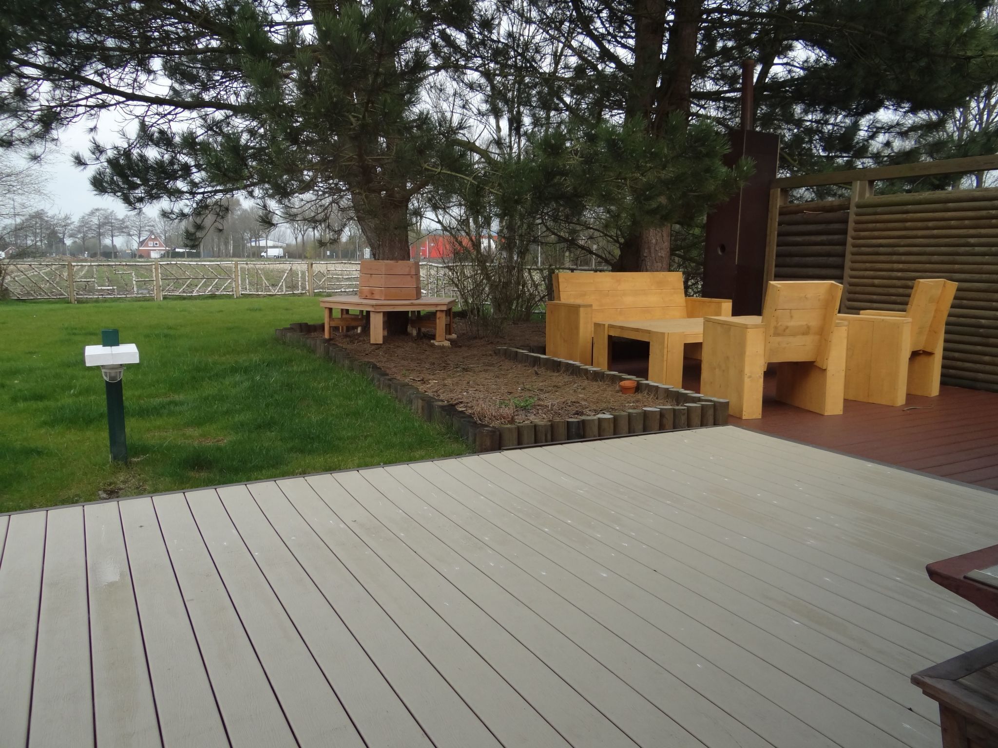 A wooden deck with outdoor furniture, a mailbox, and a tree.