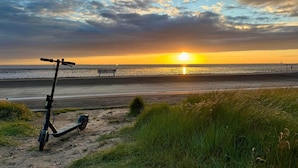 A sunset over a beach with a scooter and a bench. - Landhaus Markus by Interhome (Süderschwei)