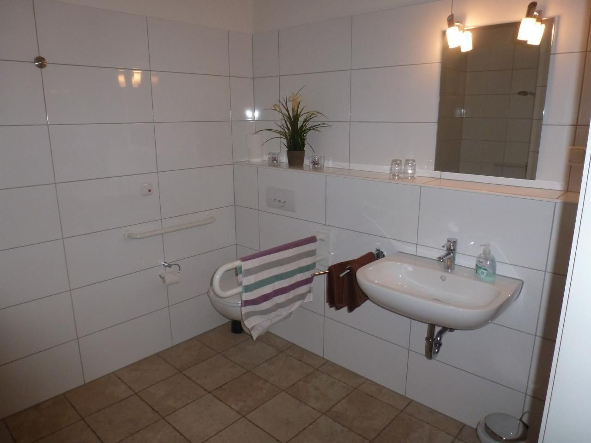 A bathroom with a toilet, sink, and mirror.