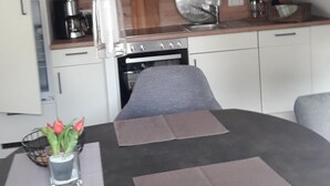 Een moderne keuken met een eethoek, inclusief een tafel met placemats, een koffiezetapparaat, een magnetron en een fornuis.