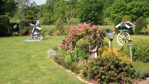 A well-maintained garden with a windmill, a birdhouse, and a decorative wheel. - Ferienhaus by Interhome (Witzeeze)