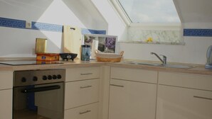 Une cuisine dotée d’une lucarne, de meubles de rangement en bois, d’une cuisinière et d’un évier.