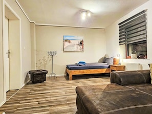 A bedroom with a bed, a bedside table, a lamp, a window with blinds, a radiator, and a painting on the wall. - Apartment Naturpark by Interhome (Selk)