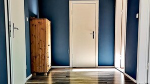 Ein Flur mit Holzboden, einem Holzschrank und drei weißen Türen.