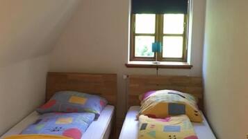 Ein kleines Schlafzimmer im Dachgeschoss mit zwei Holzbettklappen, einem Fenster mit Aussicht und einer Deckenleuchte.