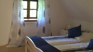 Un dormitorio con una cama de madera, una mesita de noche, una lámpara y una ventana con cortinas.