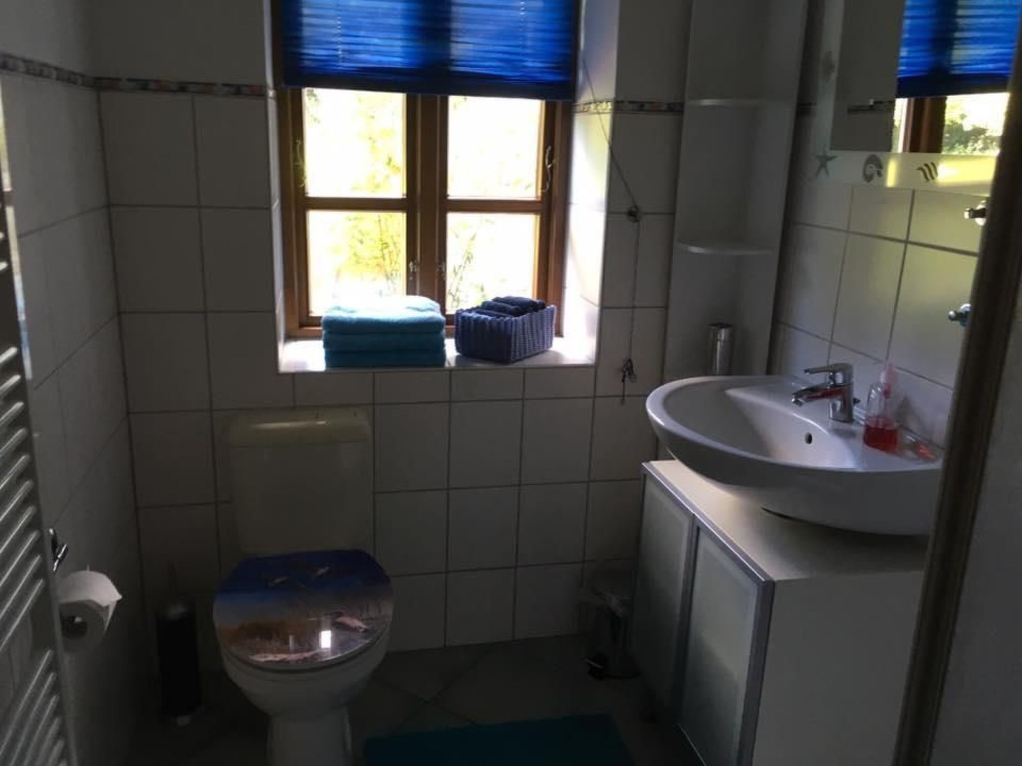 Un baño pequeño con inodoro, lavamanos y ventana con vistas a la vegetación.