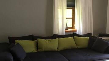 Una sala de estar con un sofá de color oscuro, una mesa de centro blanca y un tapete verde.