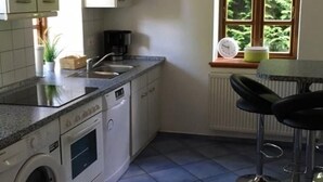 Cocina compacta con lavadora, un lavamanos y ventana con vistas a zonas verdes.