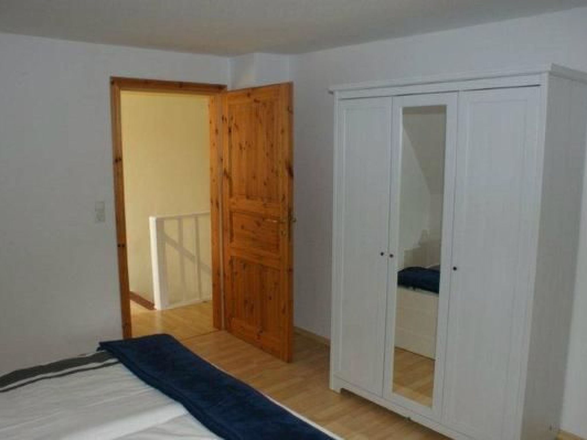 Une pièce comprenant un lit, une armoire et une porte donnant sur une autre pièce.