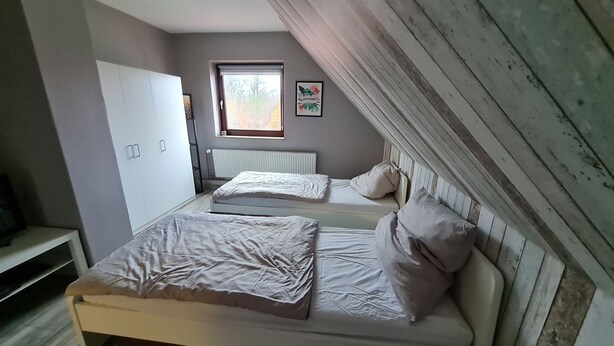 Una camera da letto con due letti, un termosifone, una finestra e un armadio.