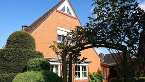 A brick house with a triangular roof, a wooden pergola, and a patio with a table and chairs. - Achtern Diek by Interhome (Laboe)