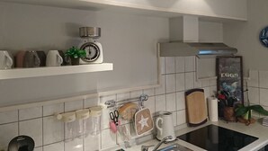A kitchen with white cabinets, a scale, a kettle, and a coffee maker. - Achtern Diek by Interhome (Laboe)