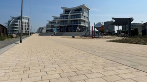 A modern building with multiple floors and balconies, a paved walkway, and a playground area. - Achtern Diek by Interhome (Laboe)