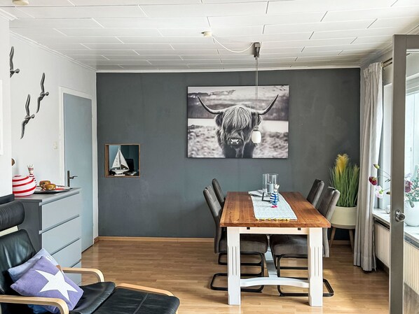 A dining area with a wooden table, chairs, and a large wall-mounted picture of a yak. - Achtern Diek by Interhome (Laboe)