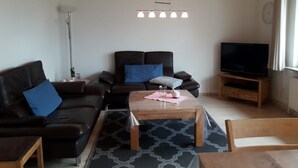 Un salon avec un canapé, une table basse, un téléviseur et une lampe.