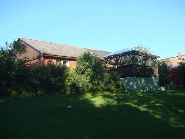 A house with a brick exterior, a sloped roof, and a covered outdoor area with a wooden structure. - in Mühlendeich mit Großem Garten by Interhome (Dagebüll)