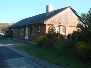 A single-story house with a sloped roof, a front porch, and a wooden fence. - in Mühlendeich mit Großem Garten by Interhome (Dagebüll)