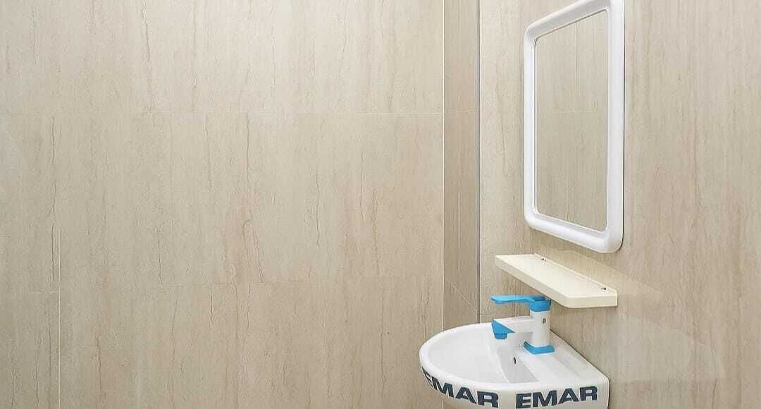 Een badkamer met een wit wastafel, een spiegel en een wandplank.