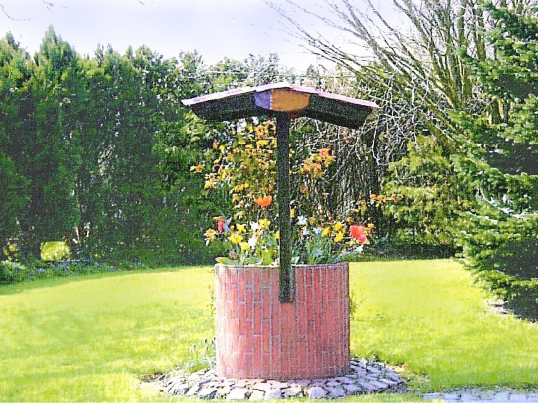 Un giardino con un vaso in mattoni al centro, ricco di fiori diversi e decorazioni.