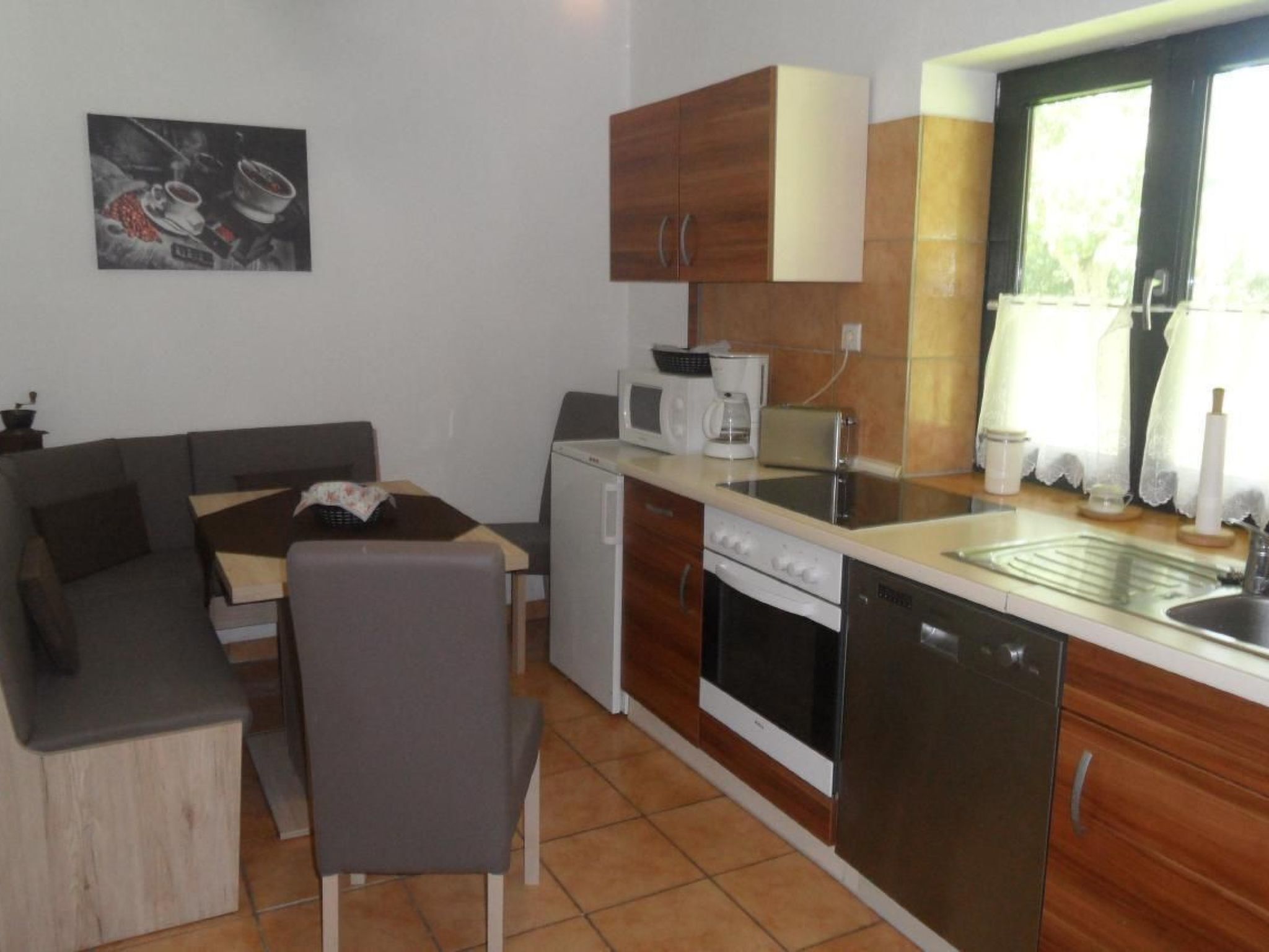 A compact kitchen with a dining area, a refrigerator, a microwave, a toaster, and a sink.