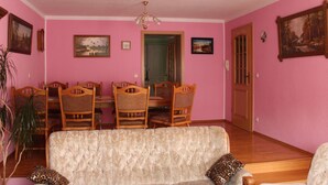 A dining area with a pink wall, wooden chairs, a table, and a sofa. - Geräumige Ferienwohnung mit Terrasse, in günstiger zentraler Lage in der Oberla by Interhome (Elstra)