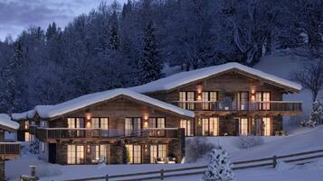 Ein großes, zweistöckiges Holzhaus mit Balkon, umgeben von schneebedeckten Bäumen.