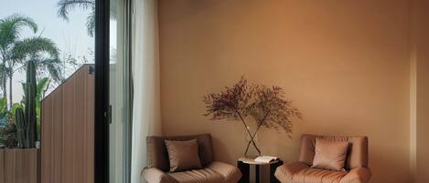 A modern room with two leather armchairs, a small table, and a vase with dried branches.
