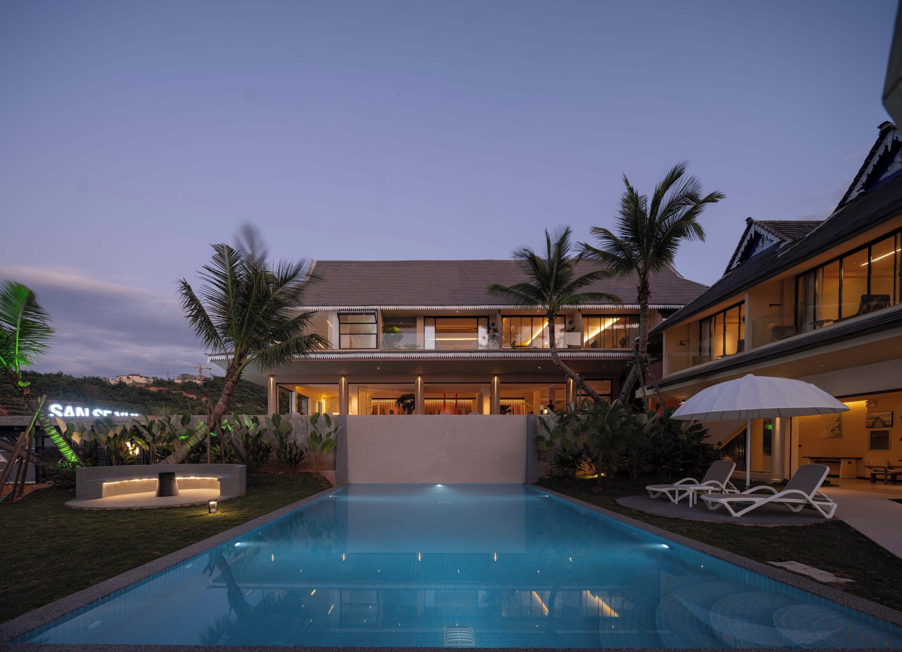 A modern two-story house with a swimming pool in the foreground.