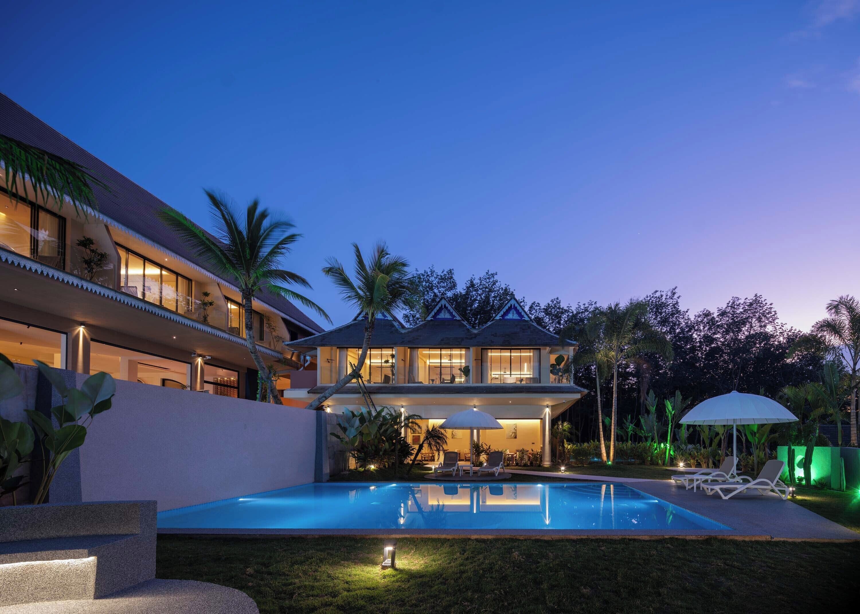 A modern house with a swimming pool, outdoor seating, and a well-maintained garden.