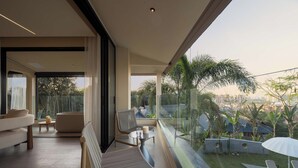 Ein moderner Balkon mit Blick auf eine Stadtlandschaft, eine Couch, ein Sessel und ein kleiner Tisch mit einer Kerze.