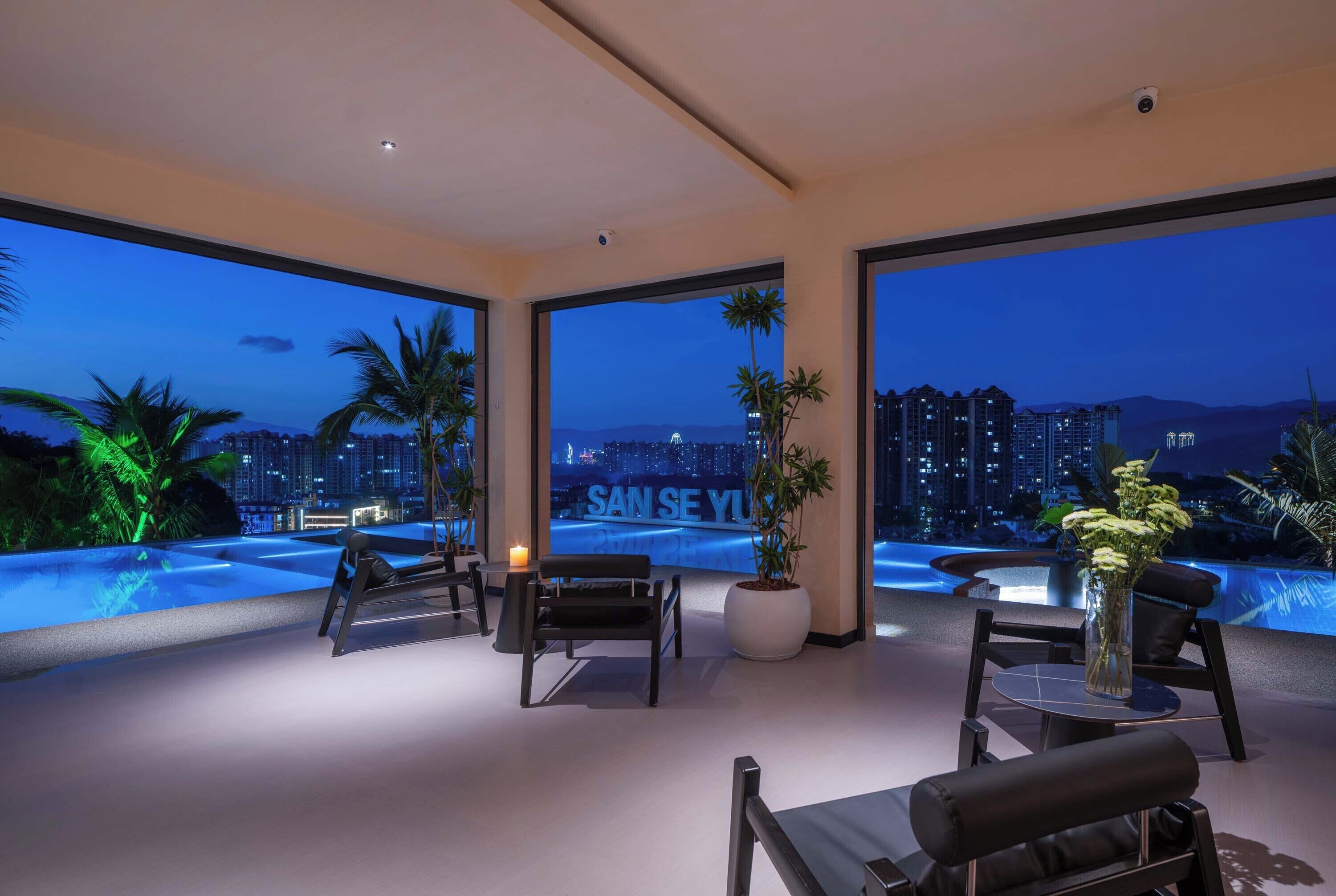 A modern rooftop lounge with panoramic city views, a pool, and comfortable seating.