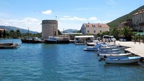 A harbor with boats, a historic tower, and a building with a red roof. - Modernes Apartment in der Nähe von Sunset Beach, WLAN, kostenloser Parkplatz by Interhome (Dubrovnik)