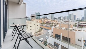 Un balcone con tavolo e sedie, vista su una città con diversi edifici e cielo sereno.