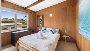 A bedroom with a bed, a desk, a window, and a painting on the wall. - The Beach House on Sixth (Anglesea)