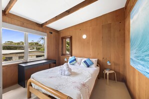 Ein Schlafzimmer mit einem Bett, einem Schreibtisch, einem Fenster und einem Bild an der Wand.