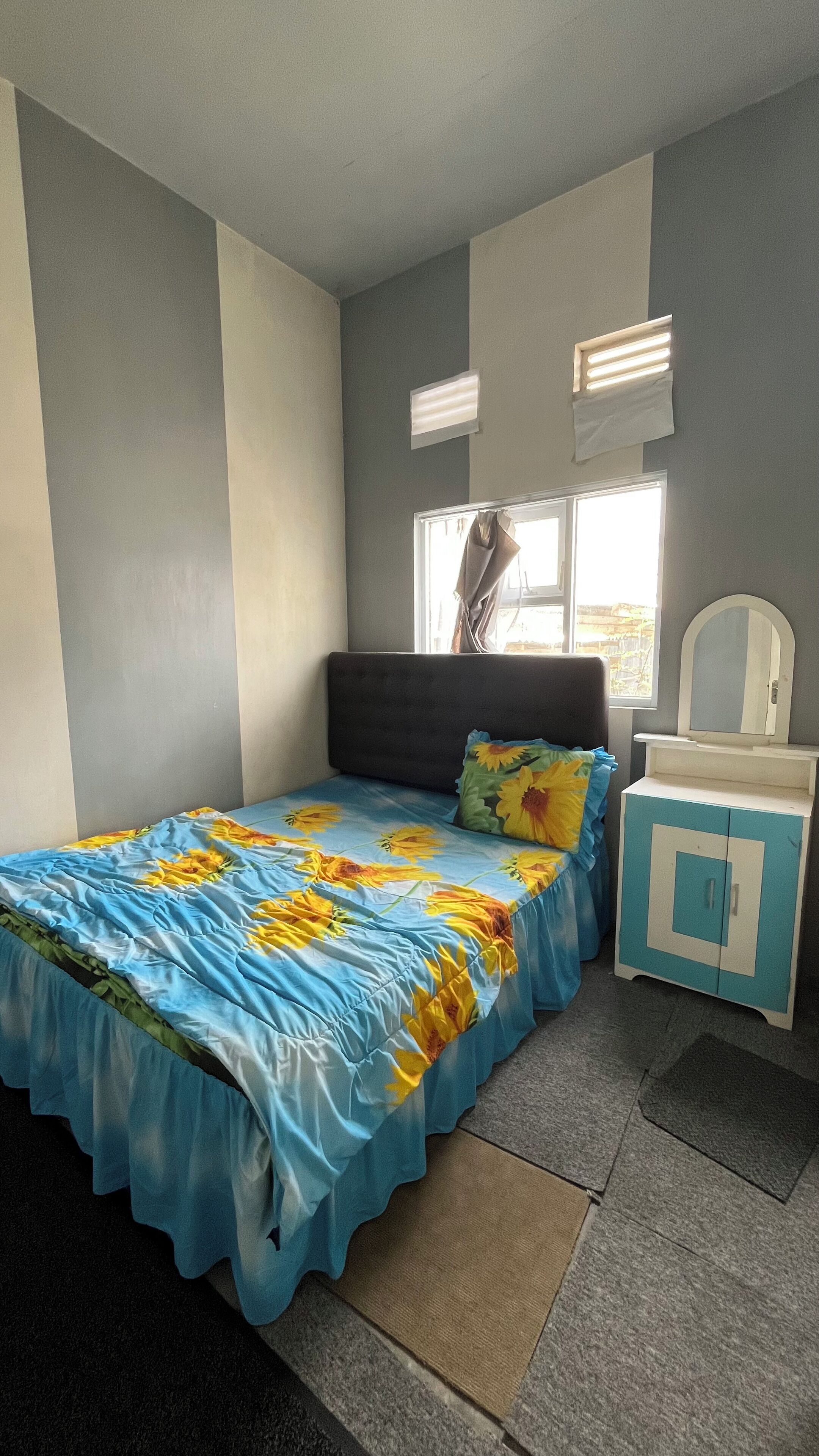 A bedroom with a bed, a nightstand, a mirror, and a window.