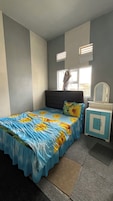 A bedroom with a bed, a nightstand, a mirror, and a window.