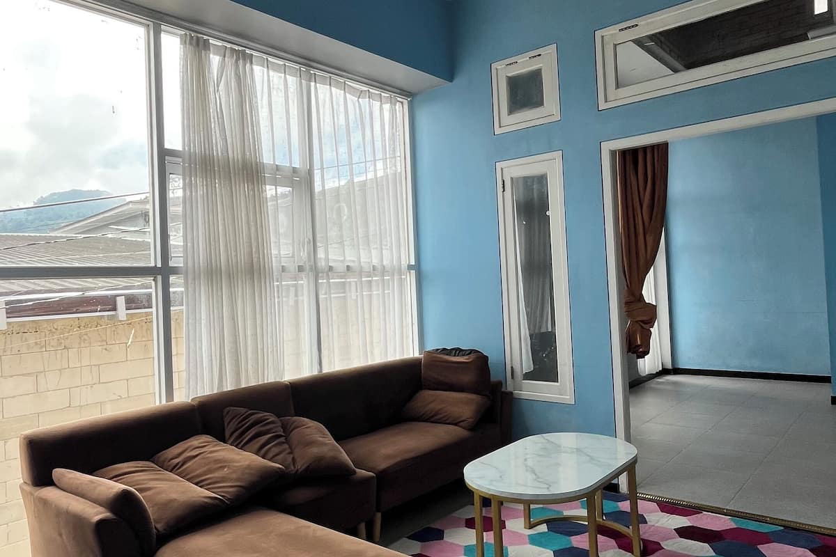 A living room with a brown sofa, a white round table, and a colorful hexagonal rug.